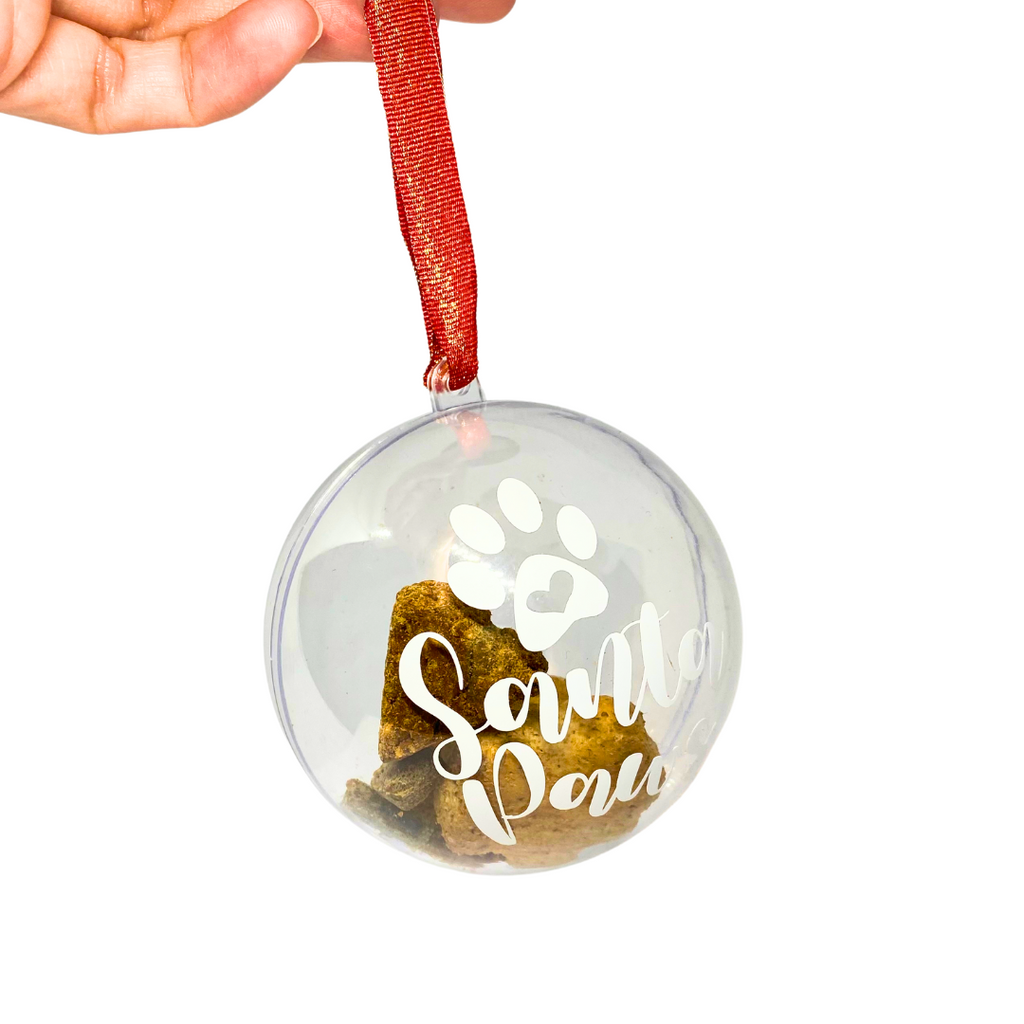 hand holding Christmas dog treat bauble with red and gold ribbon