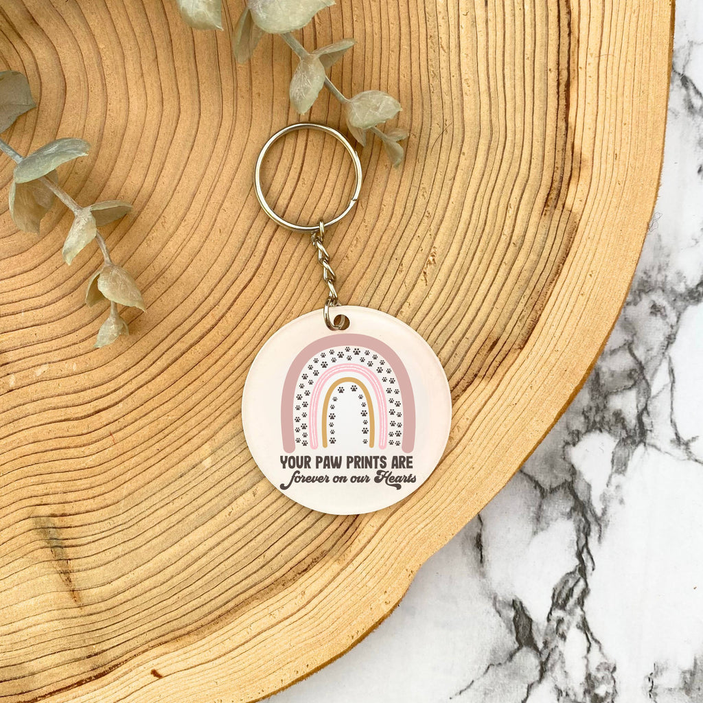 Acrylic keyring with rainbow and 'your paw prints are forever on our hearts' design on wooden background