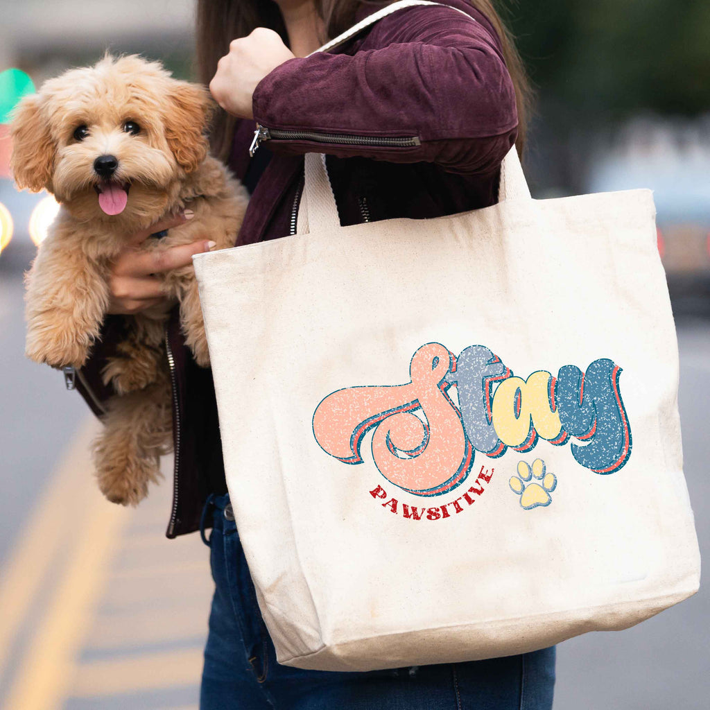 woman carrying 'Stay Pawsitive' tote bag and dog